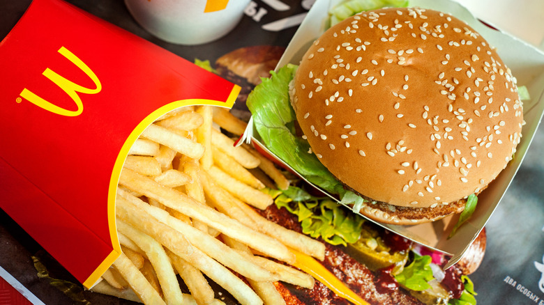 Red box of McDonald's fries next to burger with sesame bun