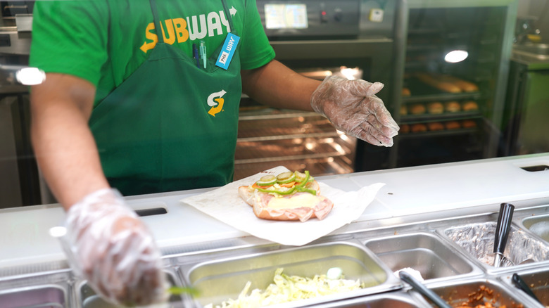 employee assembling sandwich at Subway