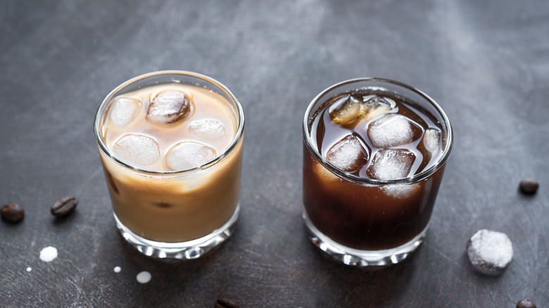 Two glasses filled with cocktails and ice on grey background