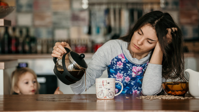 A toddler watching her mother pour coffee