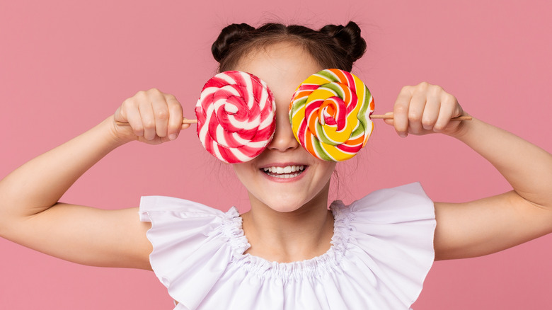 Girl holding lollipops in front of her eyes