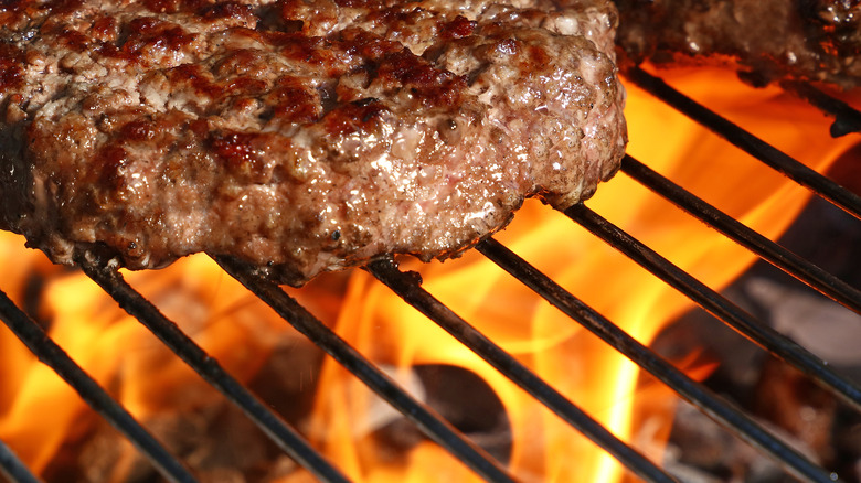 Burger patty over grill flames