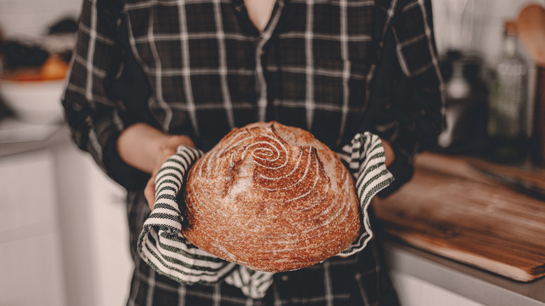 Person holding a loaf of sourdough bread