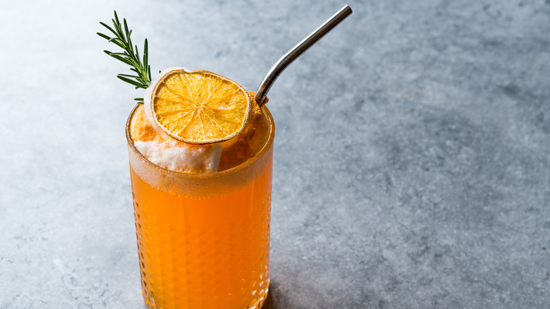 Orange cocktail with metal straw and rosemary