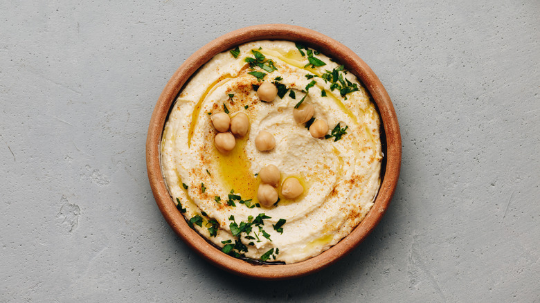 Brown bowl full of hummus and chickpeas