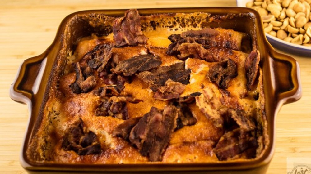 Flygande Jacob, a casserole, pictured from the original 1976 recipe. It is in a square brown casserole dish. The casserole is light brown and topped with bacon.