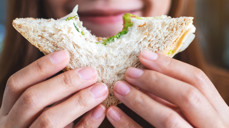 Woman holding a sandwich with a bite taken out of it 
