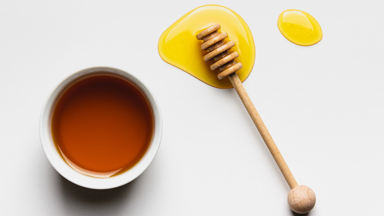 Honey in a bowl next to honey drizzler 