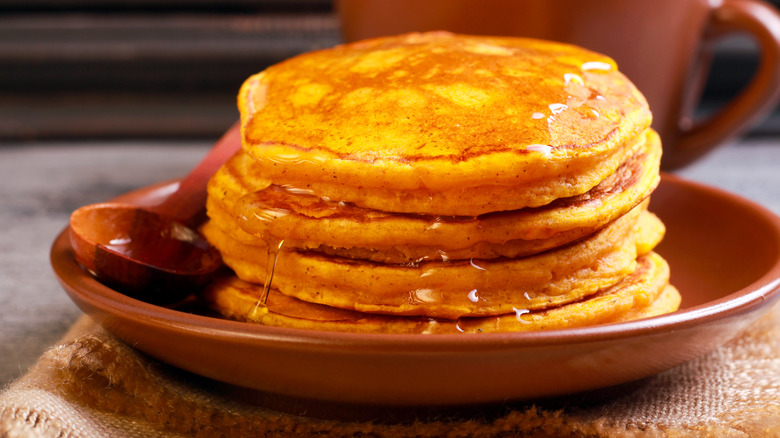 Pumpkin pancakes with syrup on brown plate