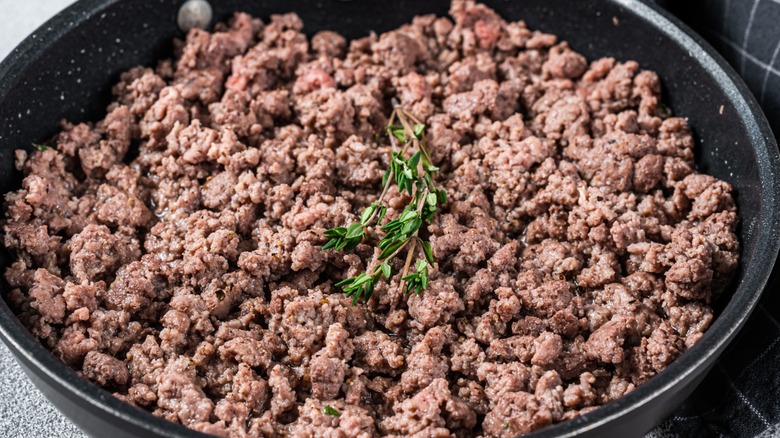 Skillet of cooked ground beef topped with thyme