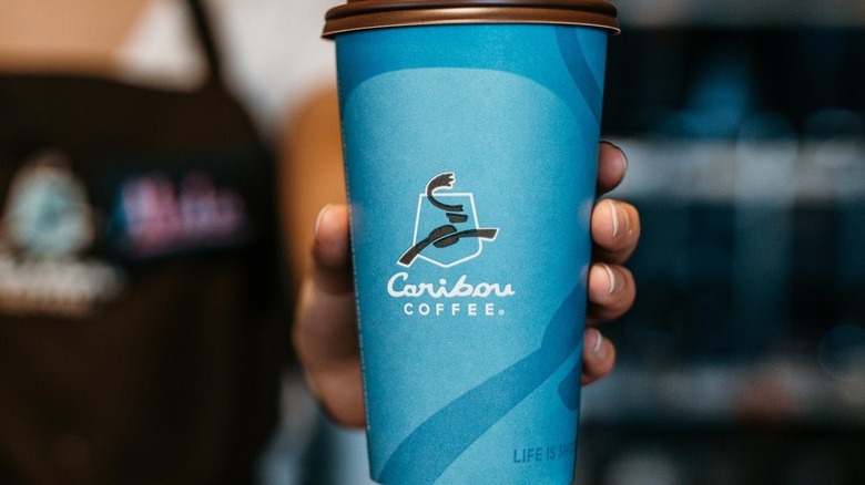 Employee holding Caribou Coffee cup