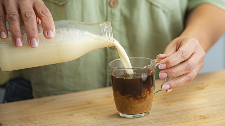 pouring milk into coffee glass