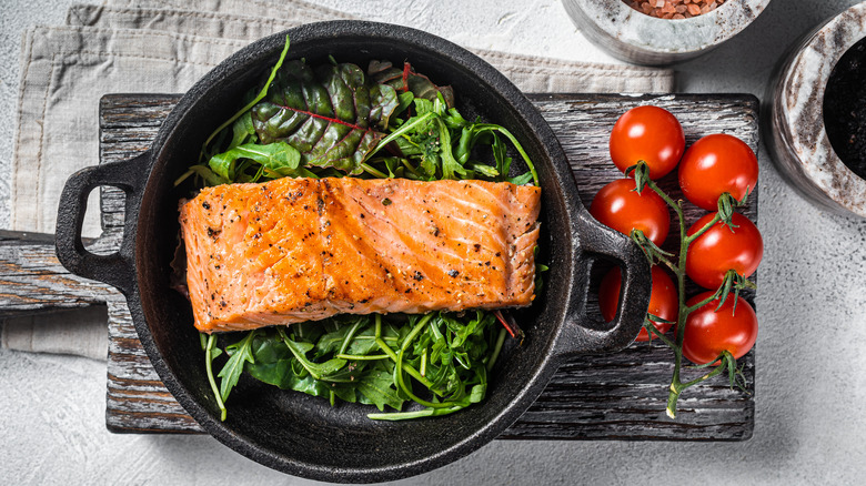 salmon in pan with tomatoes and salad