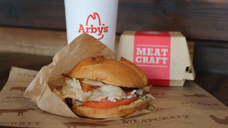 Arby's chicken sandwich and a drink in the background