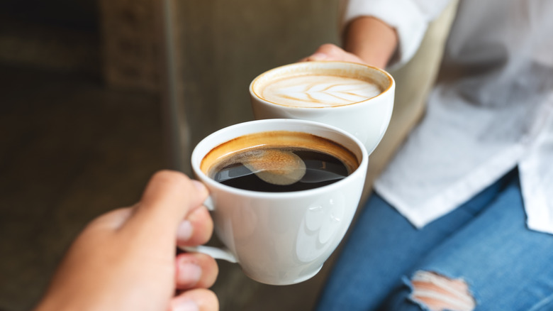 two people cheersing with coffee mugs