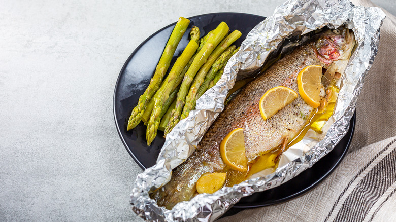 Salmon cooked in tinfoil alongside asparagus stalks