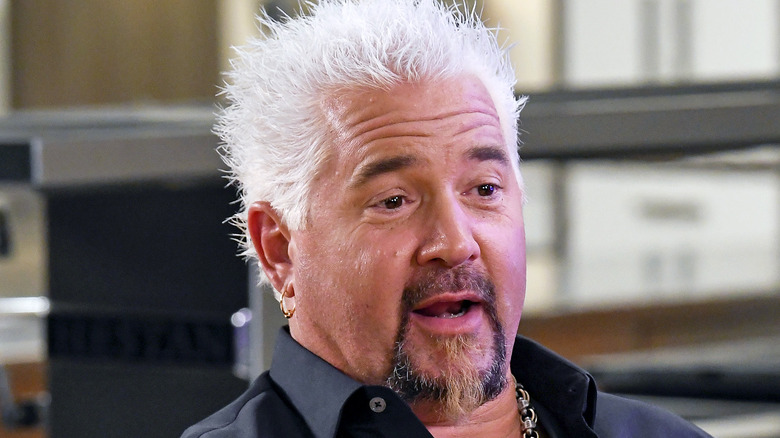 Guy Fieri talking wearing a dark button down shirt