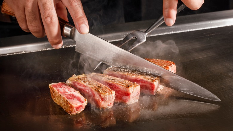 Slicing steak on hibachi grill 