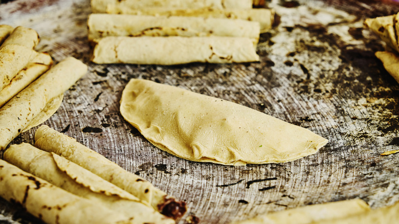 Fresh tortillas being rolled into flautas