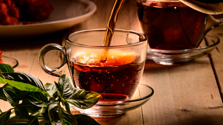 Someone pouring tea into a translucent cup