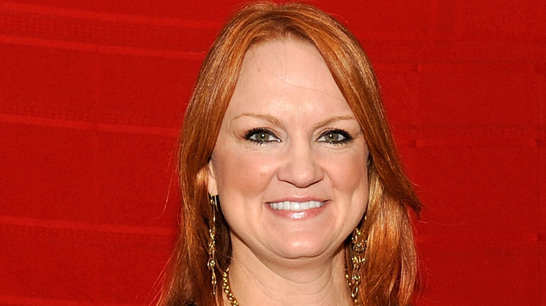Ree Drummond with gold earrings and red background