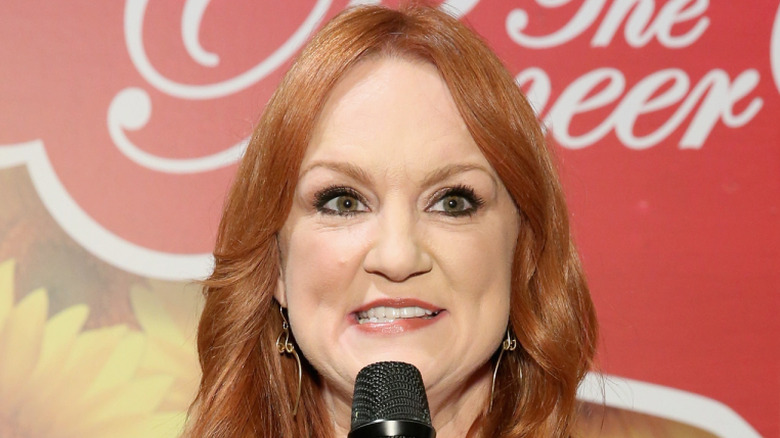 Ree Drummond with floral backdrop holding a microphone