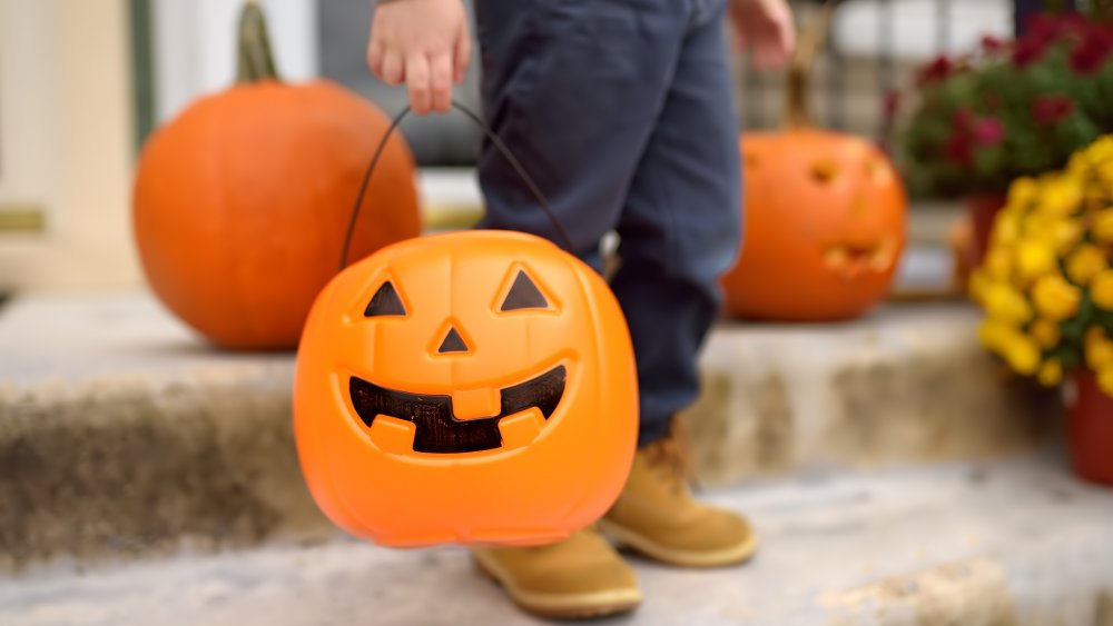 child with pumpkin-shaped halloween bucket