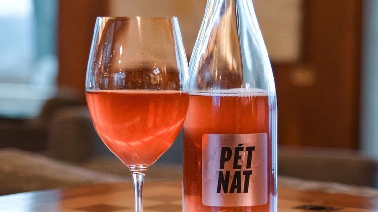 Glass of pét-nat with bottle