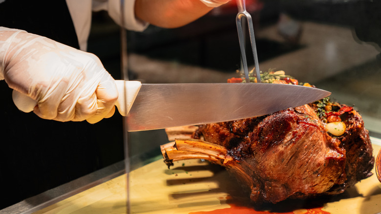 Chef slicing prime rib on cutting board