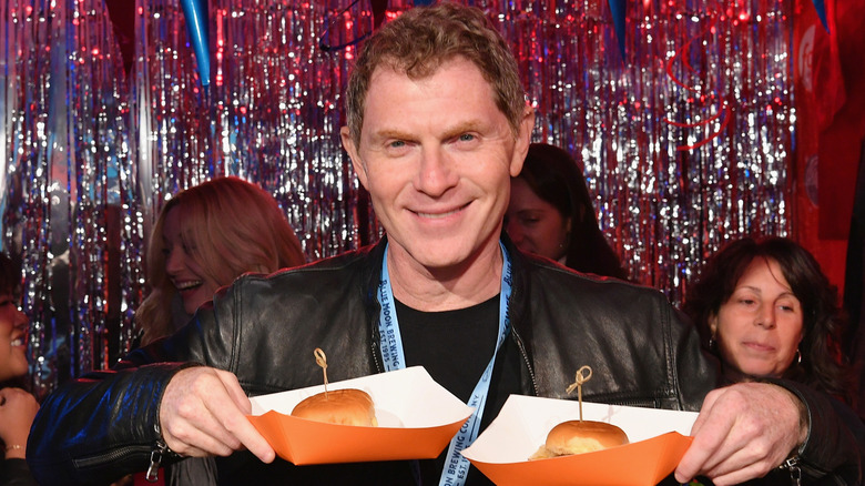 Bobby Flay holding sliders