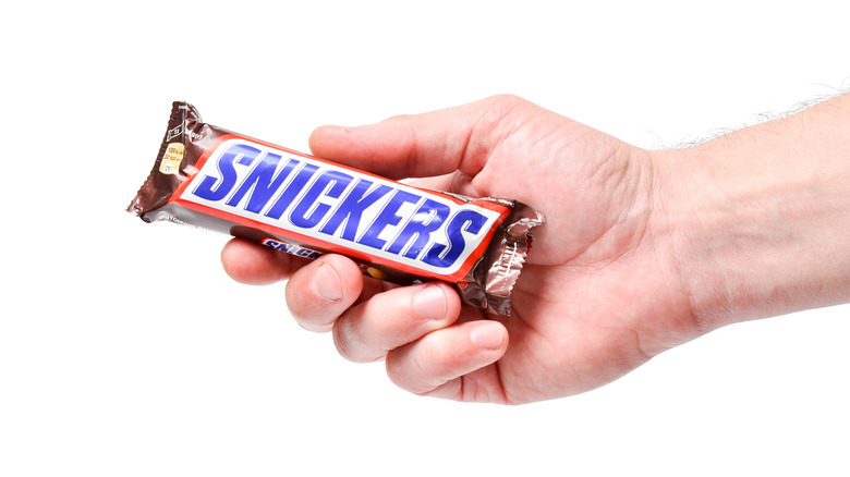 Hand holding wrapped Snickers bar