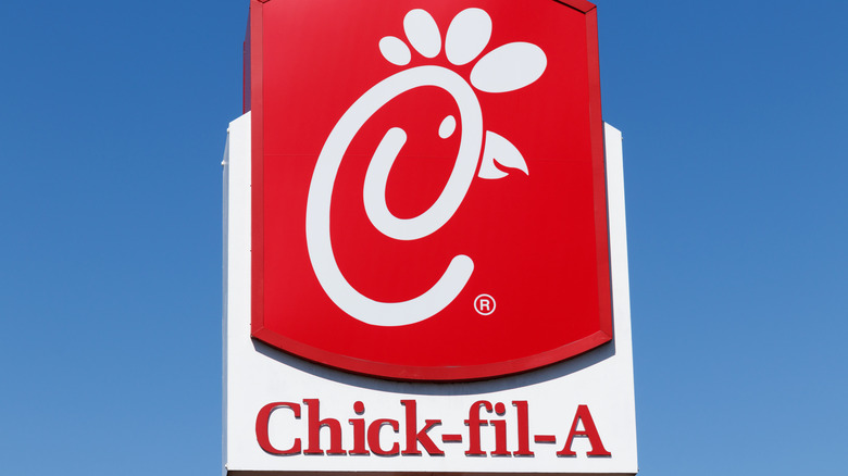 Red and white Chick-fil-A sign on blue sky background