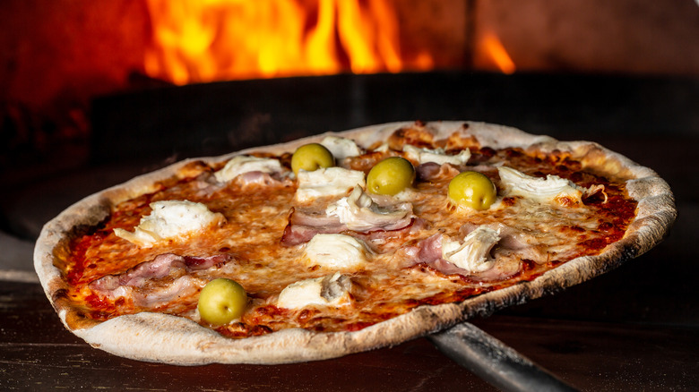 pizza pie going into a wood burning oven