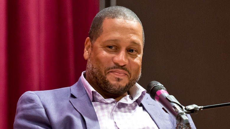 Pat Neely with slight frown seated in front of microphone