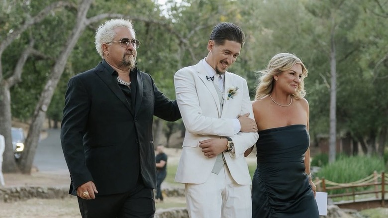 Lori and Guy Fieri with Hunter wearing wedding attire outdoors