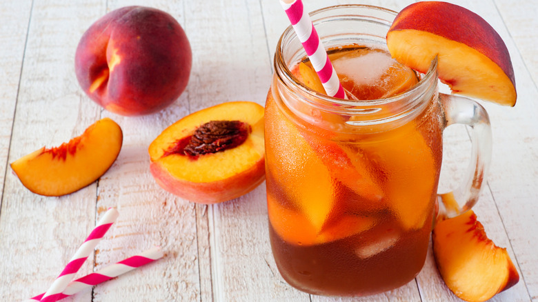 glass of peach iced tea and fresh peaches