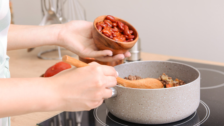 Person cooking chili on stove