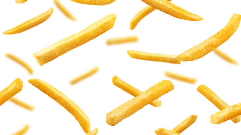 Flying French fries on white background