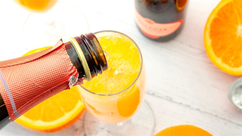 Champagne being poured into glass with orange juice