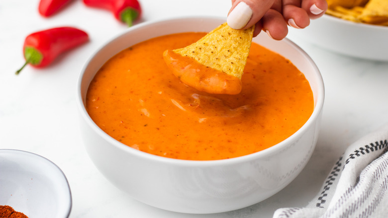 Person dipping chip in orange sauce