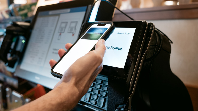 man paying at register with smartphone