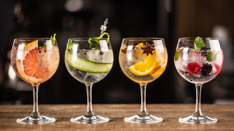 row of cocktails with fruit garnish in wine glasses