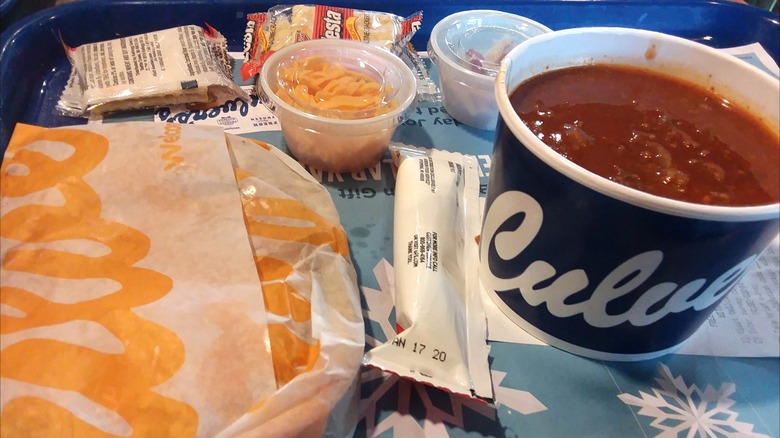 Fast food tray with Culver's grilled cheese in wrapper, tomato Florentine soup in a cup, and condiments