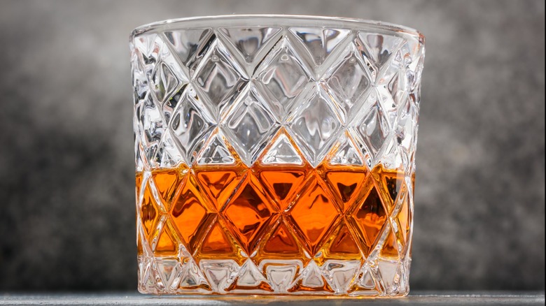 Glass of bourbon on barrel