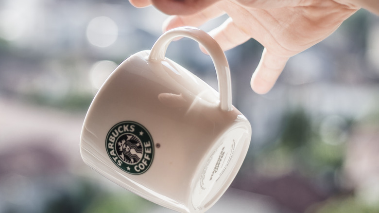 a starbucks coffee mug falling from a hand