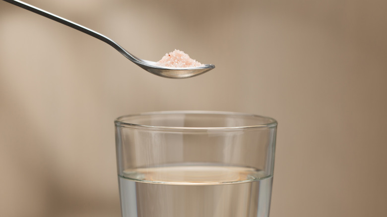 Pink salt held above a water glass