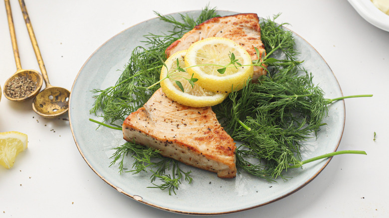 cooked swordfish on plate with lemon slices