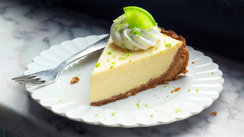 Key lime pie slice on white plate with fork