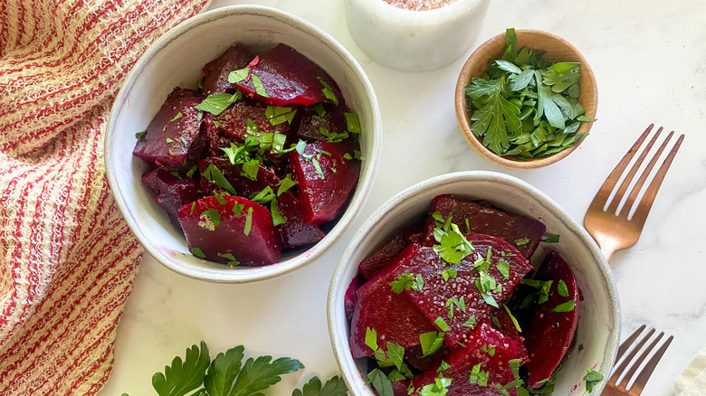 two bowls of pickled beets with cilantro and forks