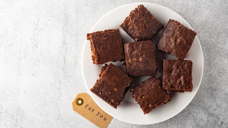 A plate of chocolate-walnut brownies next to a note that says "for you"